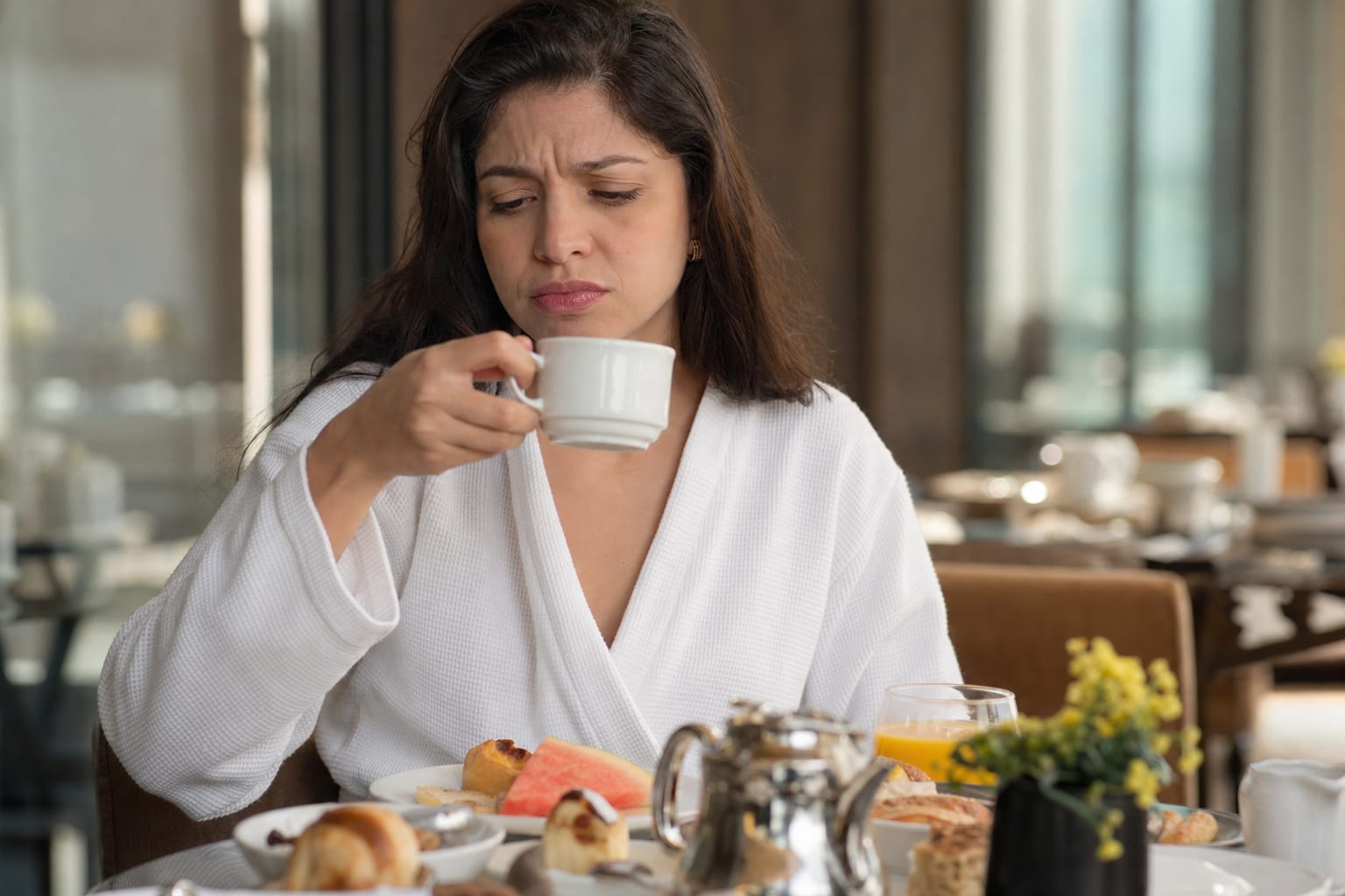 hospede-de-hotel-com-uma-expressao-sutil-de-insatisfacao-ao-saborear-cafe-na-mes